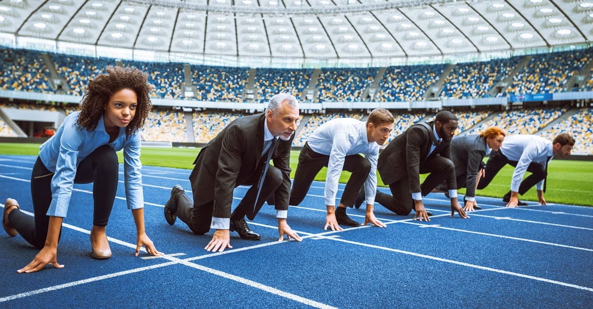Side view photo of confident multi ethnic business people lined up getting ready for race on track in a stadium. Personal ambition